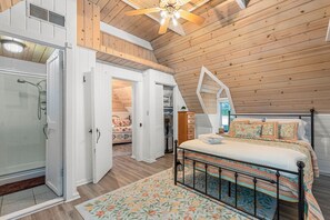 Ein Schlafzimmer mit einem Bett, einer Holzbalkendecke und einer Duschkabine.