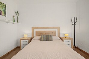 A neatly arranged bedroom with a wooden headboard, two bedside tables with lamps, a striped pillow, and a floor lamp. - Room 'Bambu' with shared terrace, Wi-Fi and air conditioning (Poblenou del Delta)
