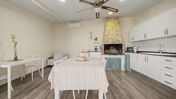 Una cocina moderna con armarios blancos, una chimenea de piedra y un comedor con mantel a rayas.