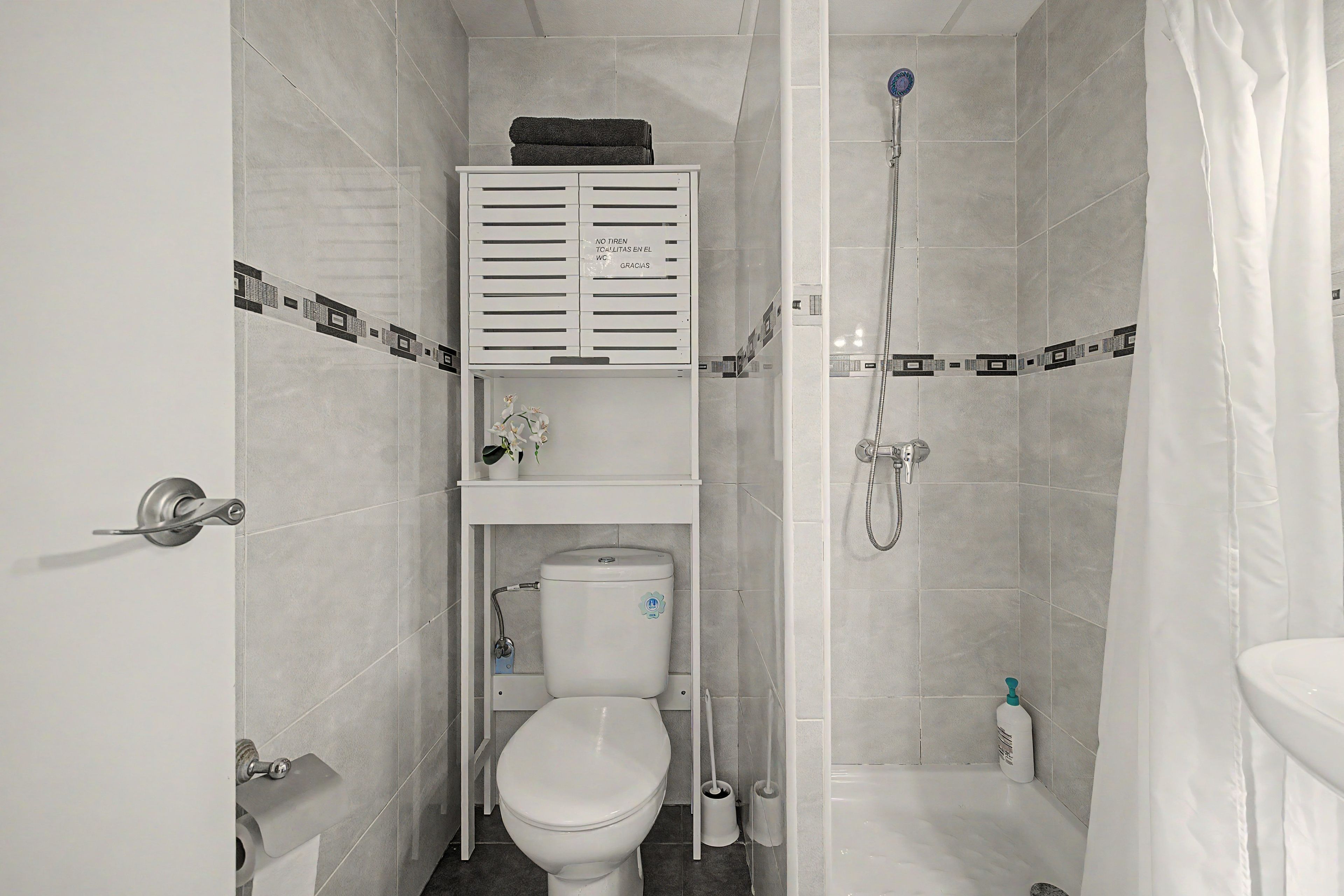 Un baño pequeño con inodoro, ducha y lavamanos.