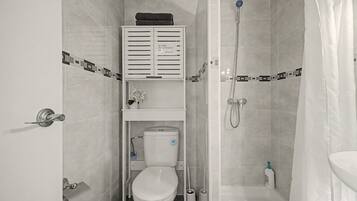 Un baño pequeño con inodoro, ducha y lavamanos.