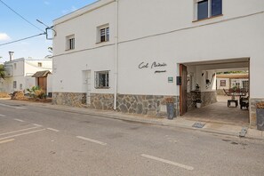 Un edifici amb façana de pedra, un rètol que diu 'Col. Music' i zones d'estar a l'exterior visibles a través de l'entrada.