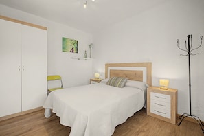 Une chambre à coucher comprenant un lit, une table de chevet, une chaise, un porte-manteau et une armoire.