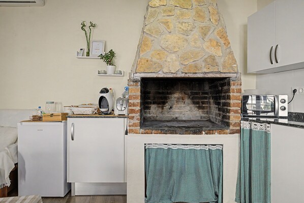 A kitchen with a stone-built oven, a refrigerator, and a microwave.