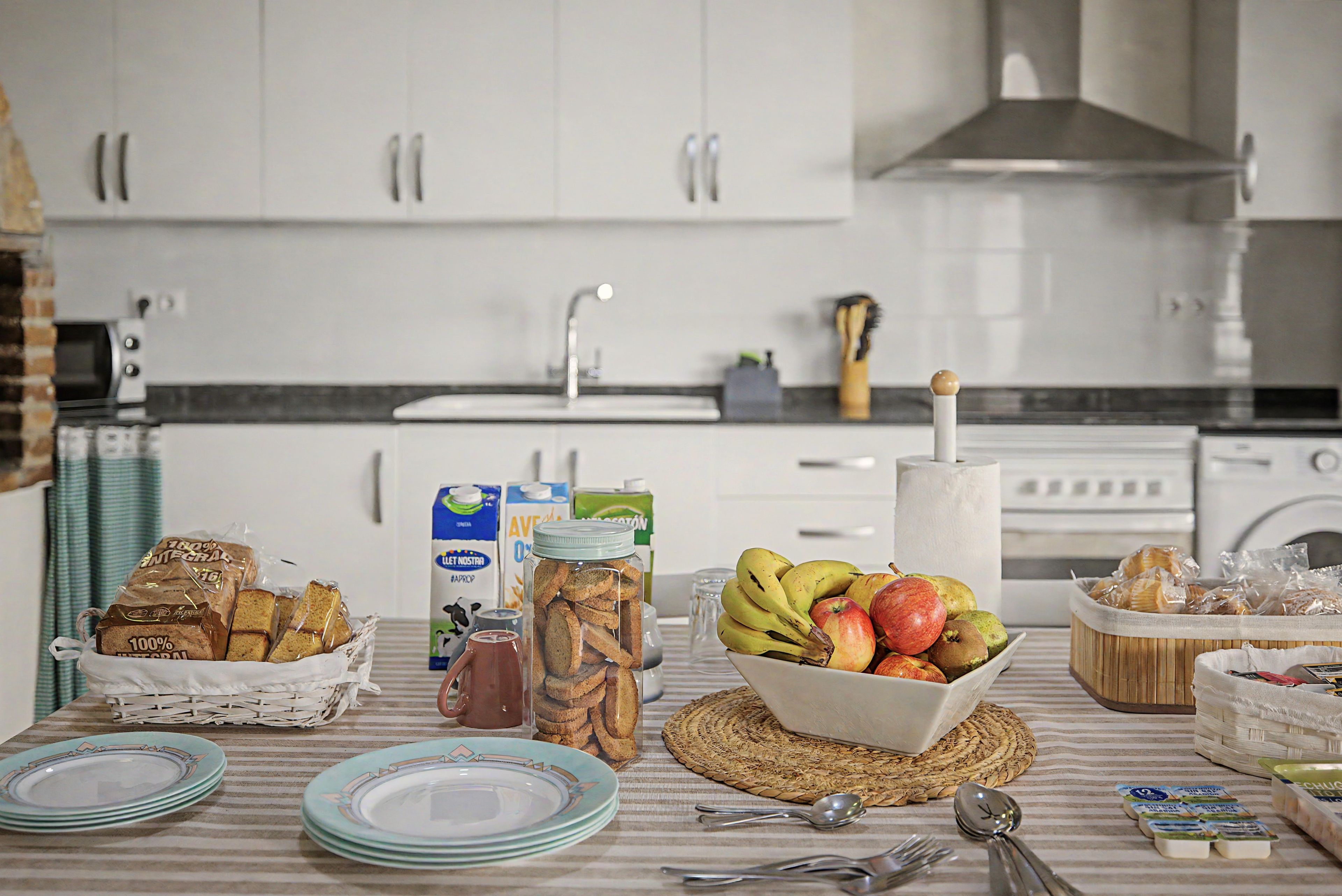 Una cocina con armarios blancos, un fregadero y diversos alimentos sobre la encimera.