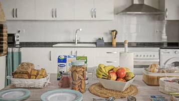 Una cocina con armarios blancos, un fregadero y diversos alimentos sobre la encimera.
