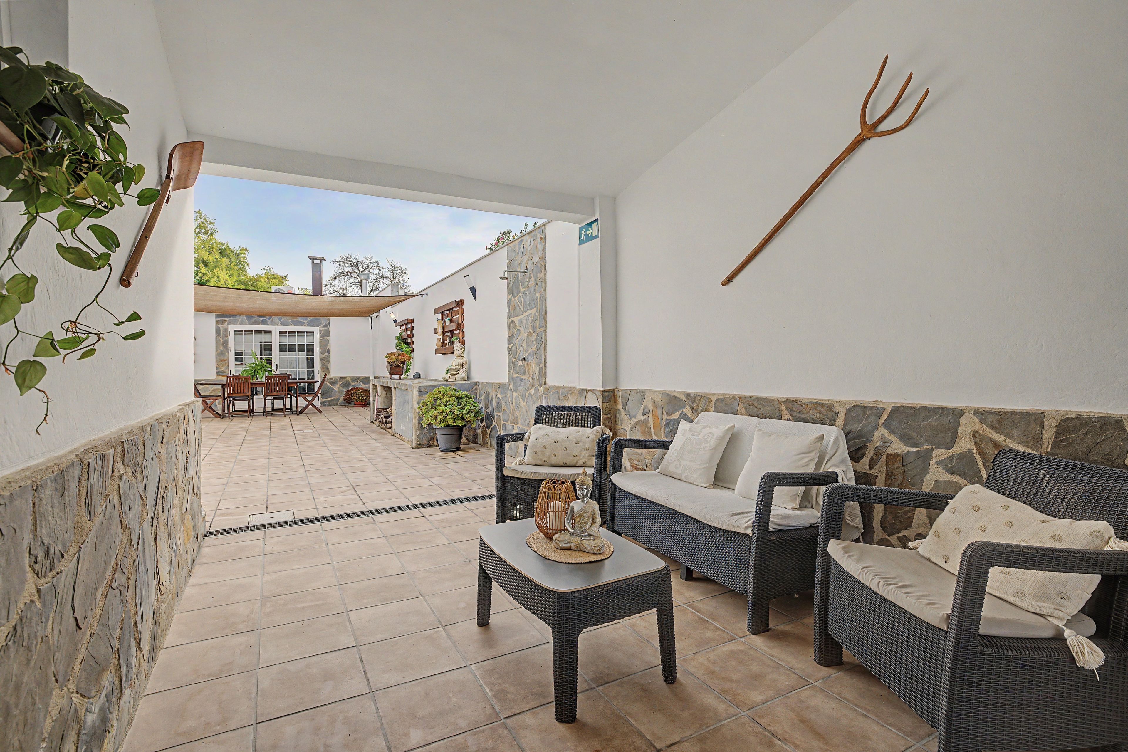Un patio con mobiliario de mimbre, una pared de piedra y una planta en maceta.