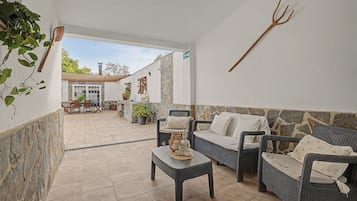 Un patio con mobiliario de mimbre, una pared de piedra y una planta en maceta.