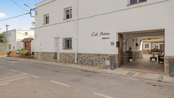Un edificio con fachada de piedra, un letrero que dice 'Col. Music' y mesas al aire libre visibles desde el acceso.