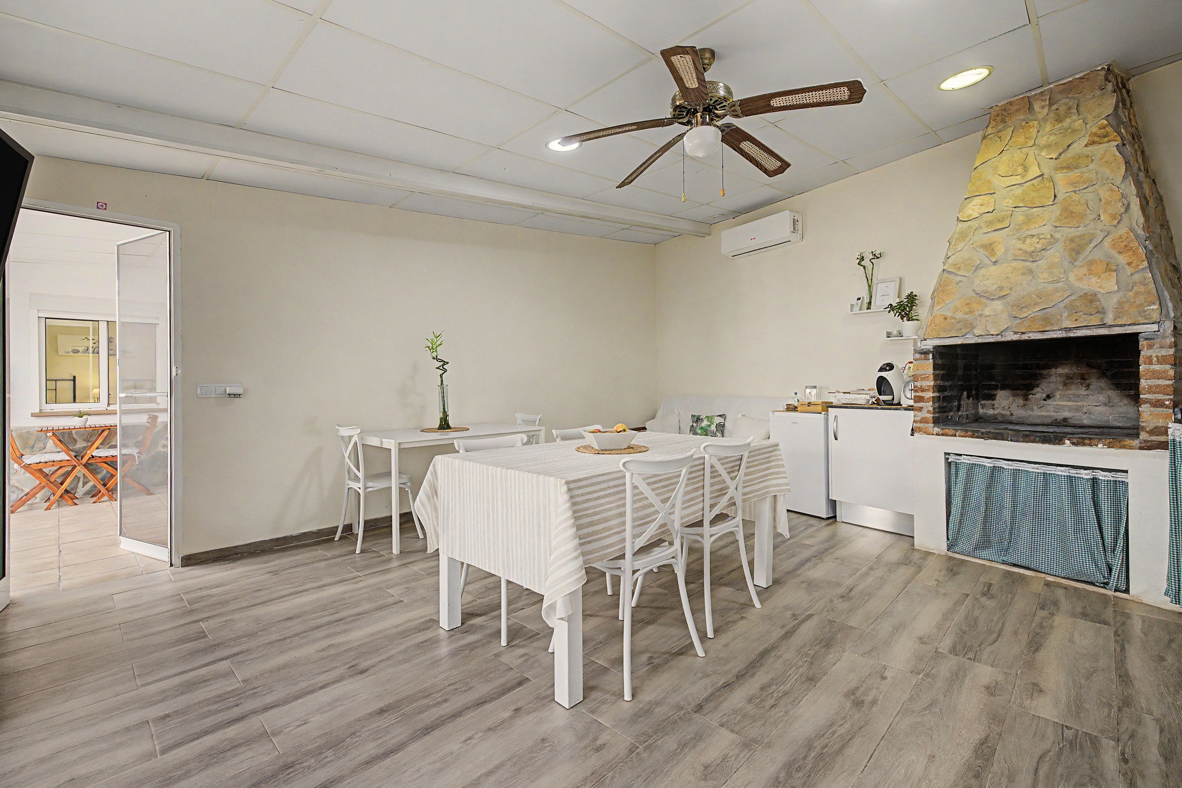 Un coin repas comprenant une table et des chaises, un ventilateur de plafond et une cheminée en pierre.