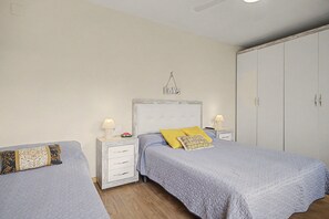 Un dormitorio con dos camas, un armario y una mesita de noche con lámparas.