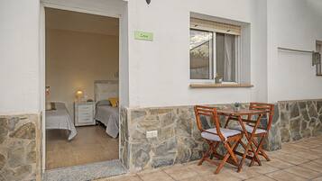 Una habitación con cama, mesita de noche, una pequeña mesa con lámpara y ventana con vistas.