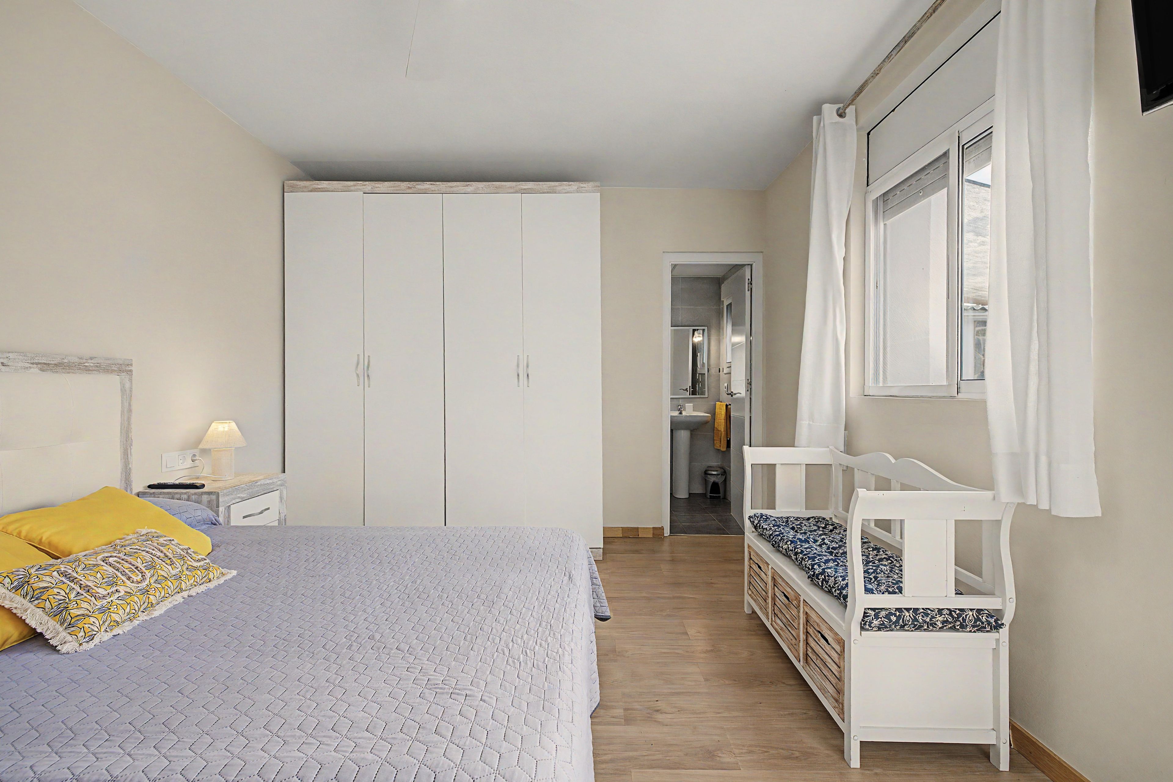 Een slaapkamer met een bed, een kledingkast, een raam en uitzicht op de badkamer.