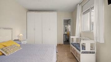 Een slaapkamer met een bed, een kledingkast, een raam en uitzicht op de badkamer.