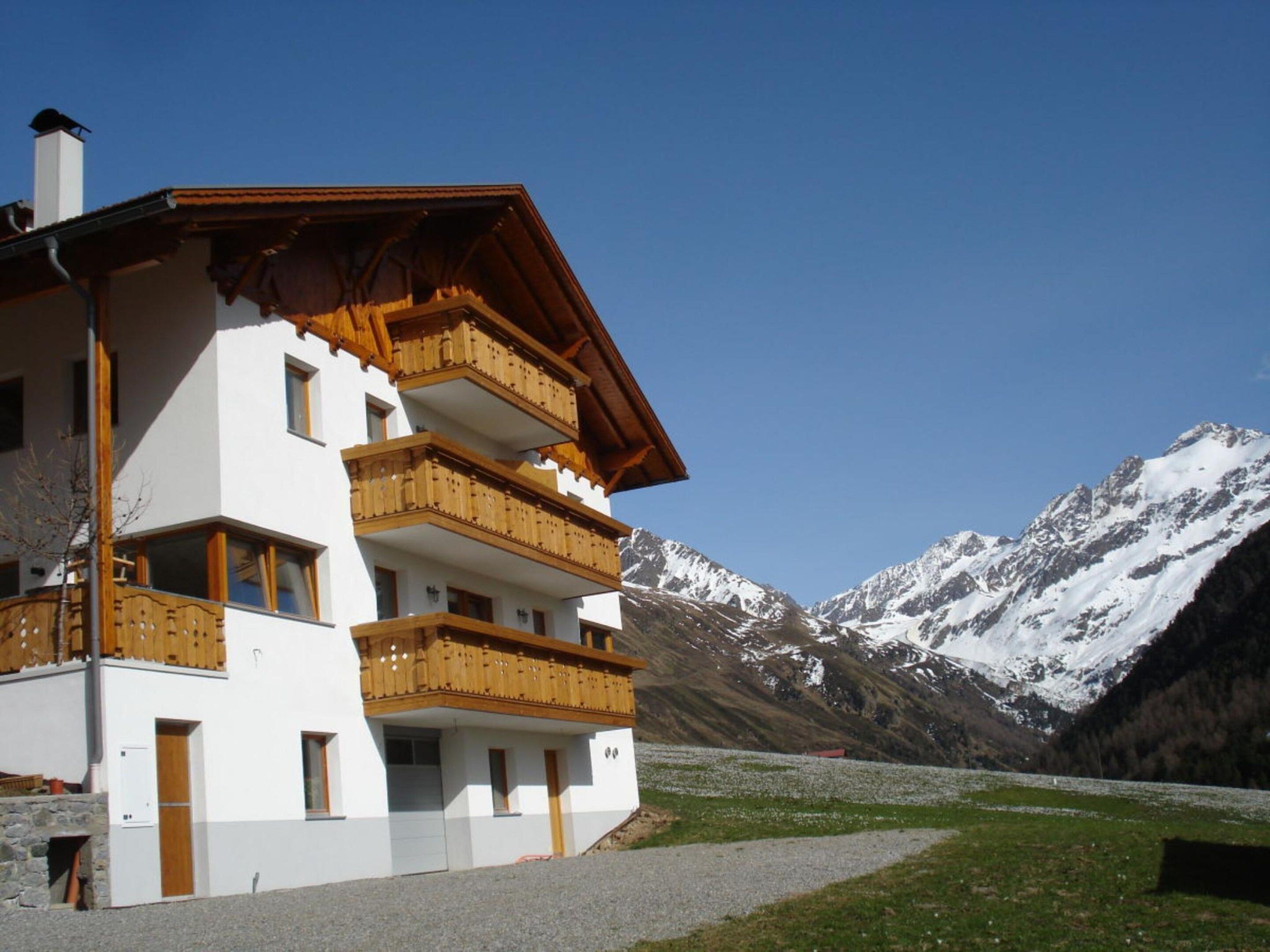 A multi-story building with wooden balconies, set against a backdrop of snow-capped mountains.