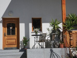 A wooden door with a window, a small table with chairs, and potted plants. - Holiday Apartment With 1 Bedroom (Curon Venosta)