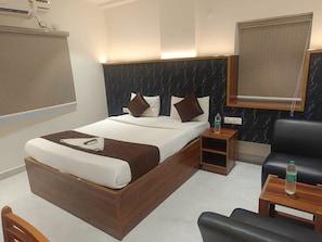 Una habitación de hotel con una cama, mesitas de noche, una silla y un espejo grande.