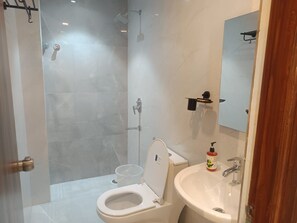 A bathroom with a shower, toilet, sink, and a mirror. - The Wise Hotel (Hyderabad)