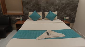 Ein Hotelzimmer mit einem Bett, zwei Nachttischen, einer Fernbedienung und einer Wasserflasche.