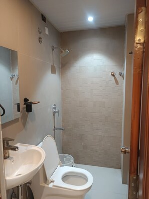 Un baño con lavamanos, inodoro y ducha blancos.