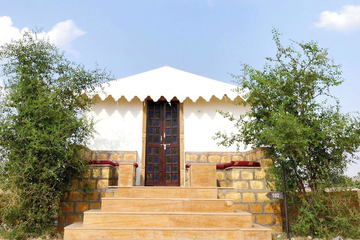 A building with a white exterior, a dark brown door, and a stone staircase leading to a red bench.