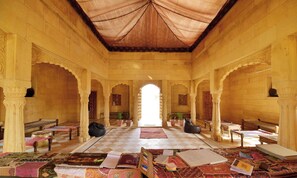 Una habitación amplia con suelo a cuadros, varias zonas de estar y un arco central.