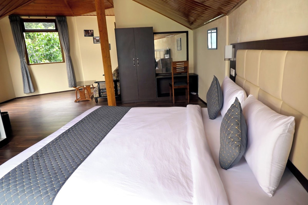 A hotel room with a large bed, a wooden headboard, a desk, and a wardrobe.