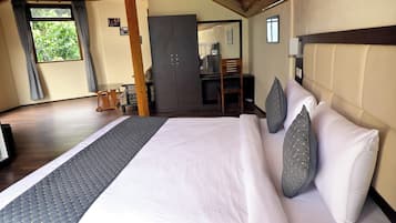 Une chambre d’hôtel avec un grand lit, une tête de lit en bois, un bureau et une armoire.