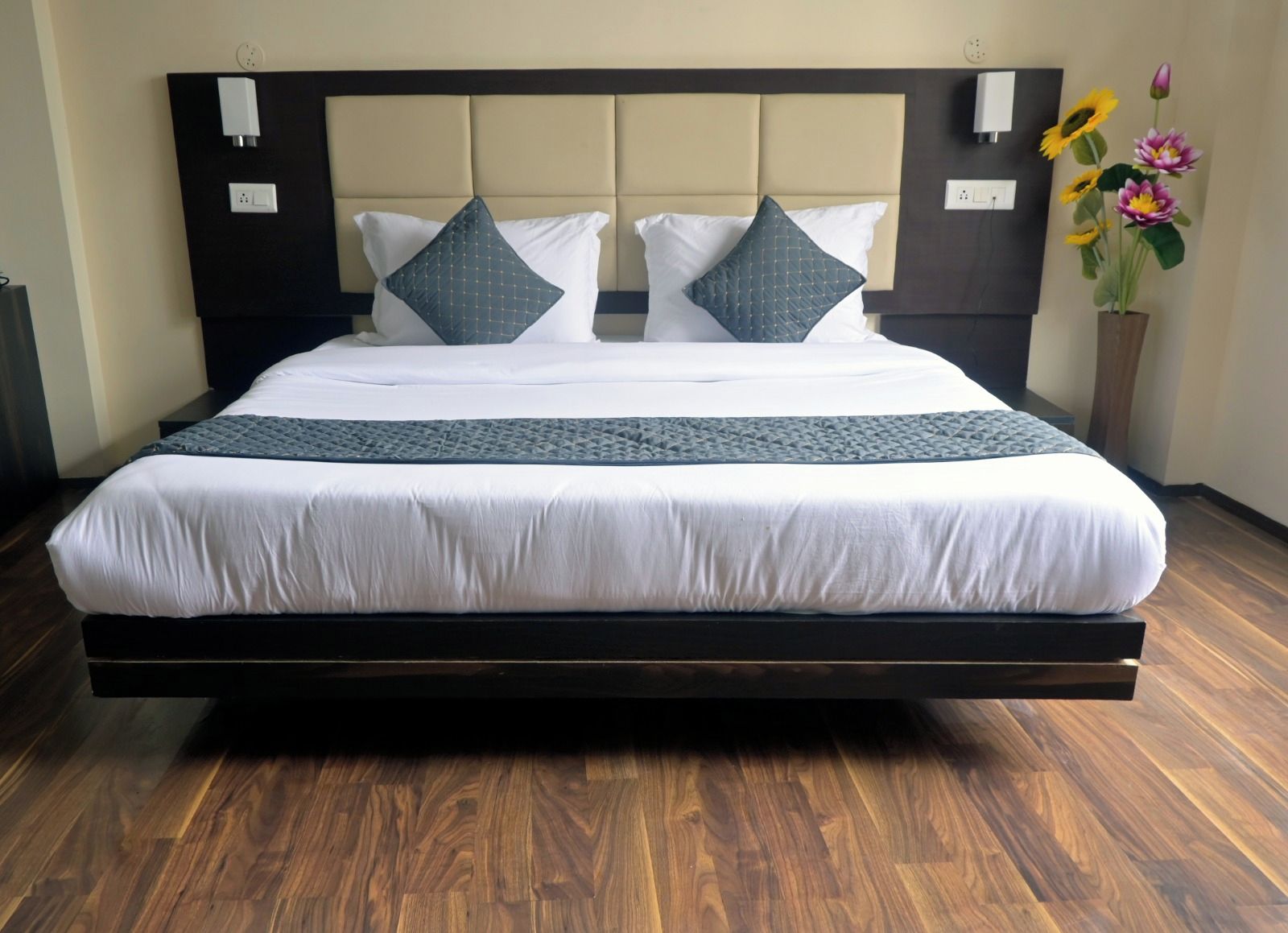 A large bed with a padded headboard, white bedding, and a dark wooden frame.