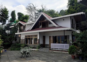 A two-story house with a balcony, a fenced yard, and potted plants. - Rumtek Heritage Resort (Rumtek)