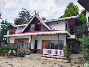 A two-story house with a red roof, white trim, and a white picket fence.