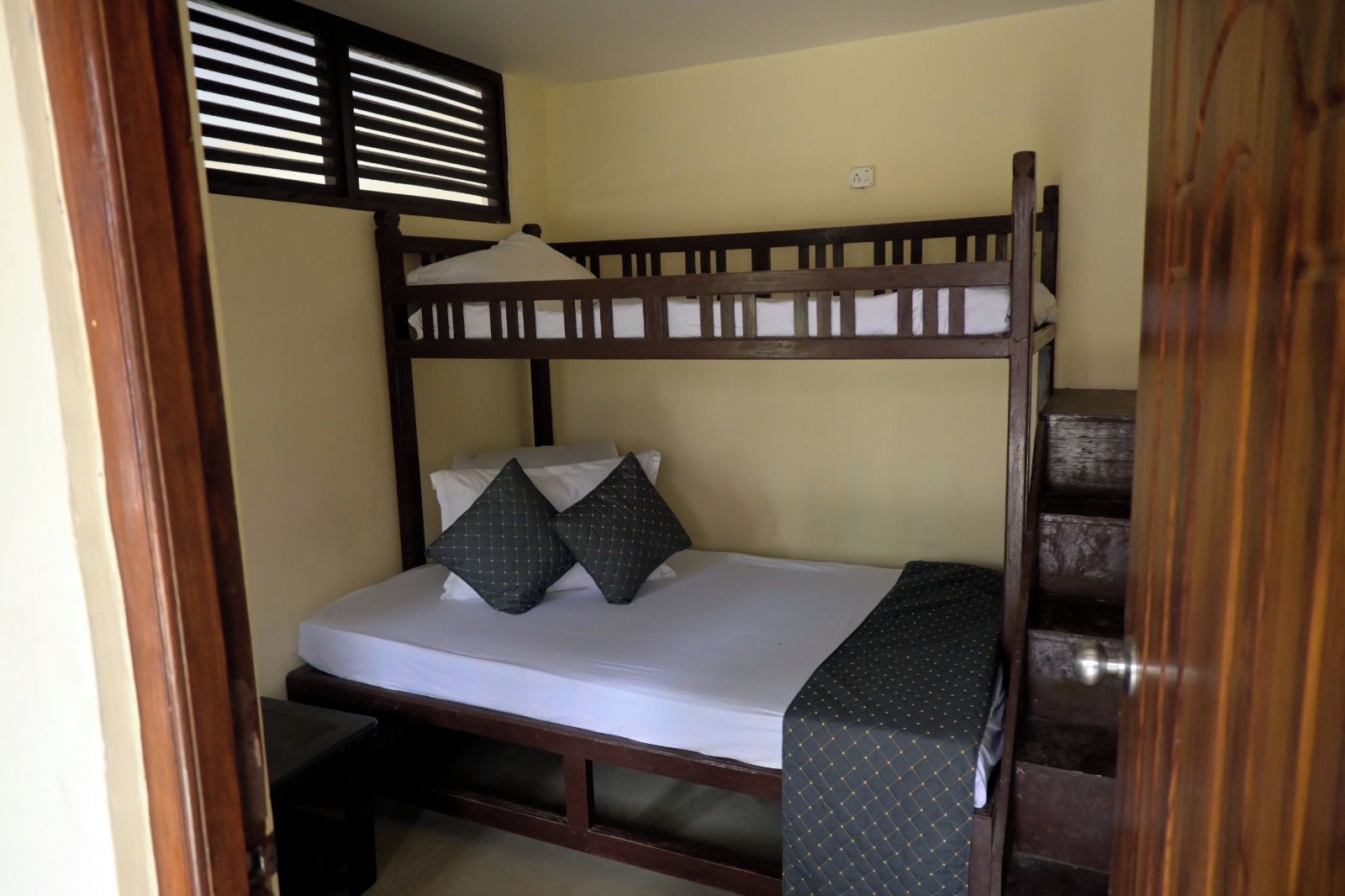 Una cama litera con estructura de madera, ropa de cama blanca y dos almohadas.