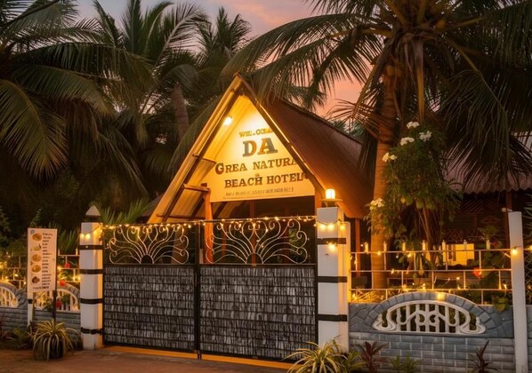 Ingresso di un hotel sulla spiaggia, con un cartello, un cancello e palme.
