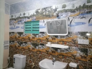 Un bagno con lavandino, specchio e una parete decorata da un murale in ceramica a tema naturale.