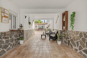 Un pasillo con paredes de piedra, un banco de madera y plantas en macetas.