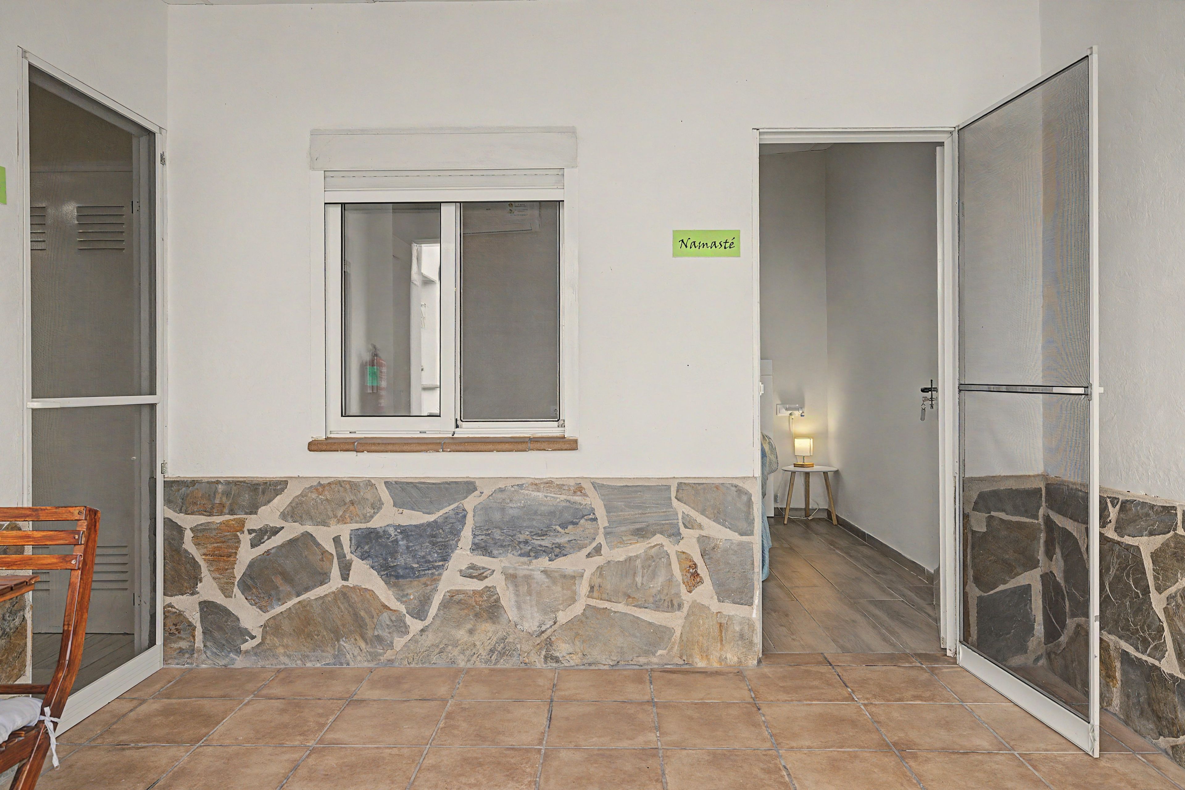 A room with a stone wall, a window with a white frame, and a door with a glass panel.