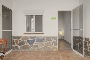 Una habitación con pared de piedra, ventana con marco blanco y puerta con panel de vidrio.