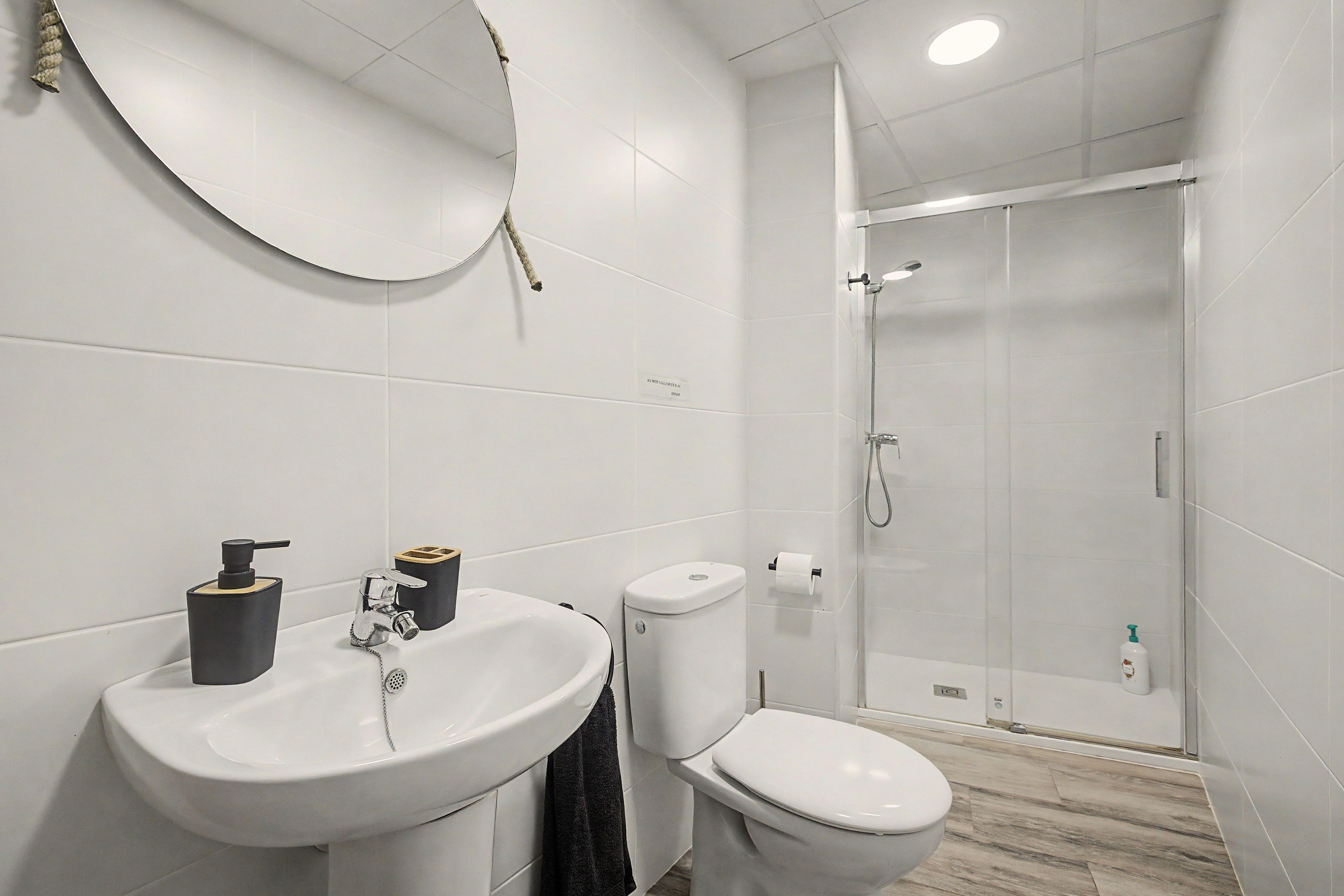 Un baño moderno con lavamanos, inodoro y ducha blancos.