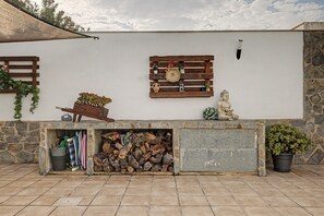 A stone wall with a wooden bench, a rustic wall-mounted shelf with decorative items, and a potted plant. - Room 'Namaste' with shared terrace, Wi-Fi and air conditioning (Poblenou del Delta)