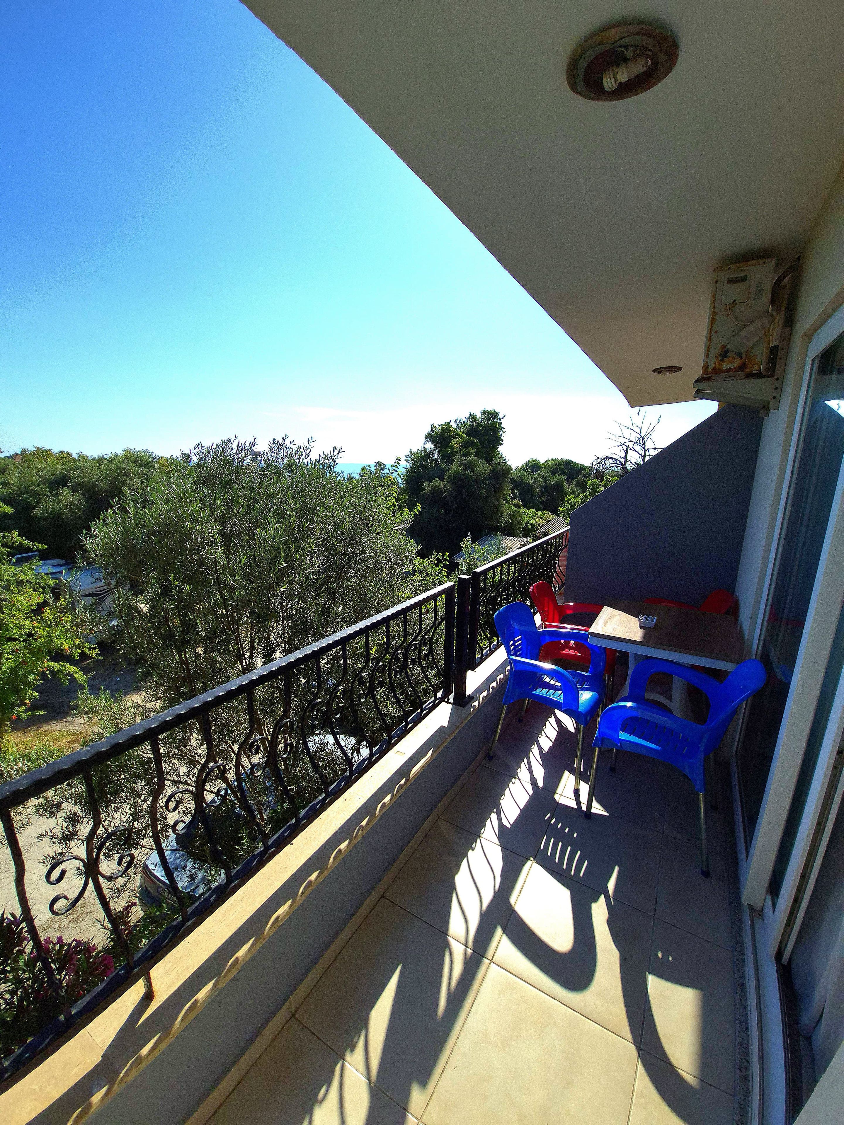Un balcon avec vue sur les arbres et un ciel dégagé.