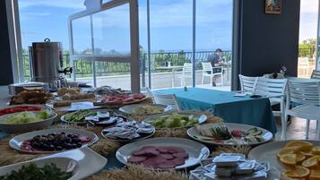 A buffet table with various food items and a view of the outdoors through large windows.