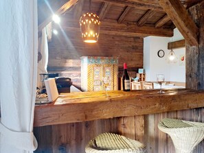 A rustic wooden interior with a bar area, wicker chairs, a wine bottle, and a decorative light fixture. - Manharthof by Interhome (Kirchberg in Tirol)
