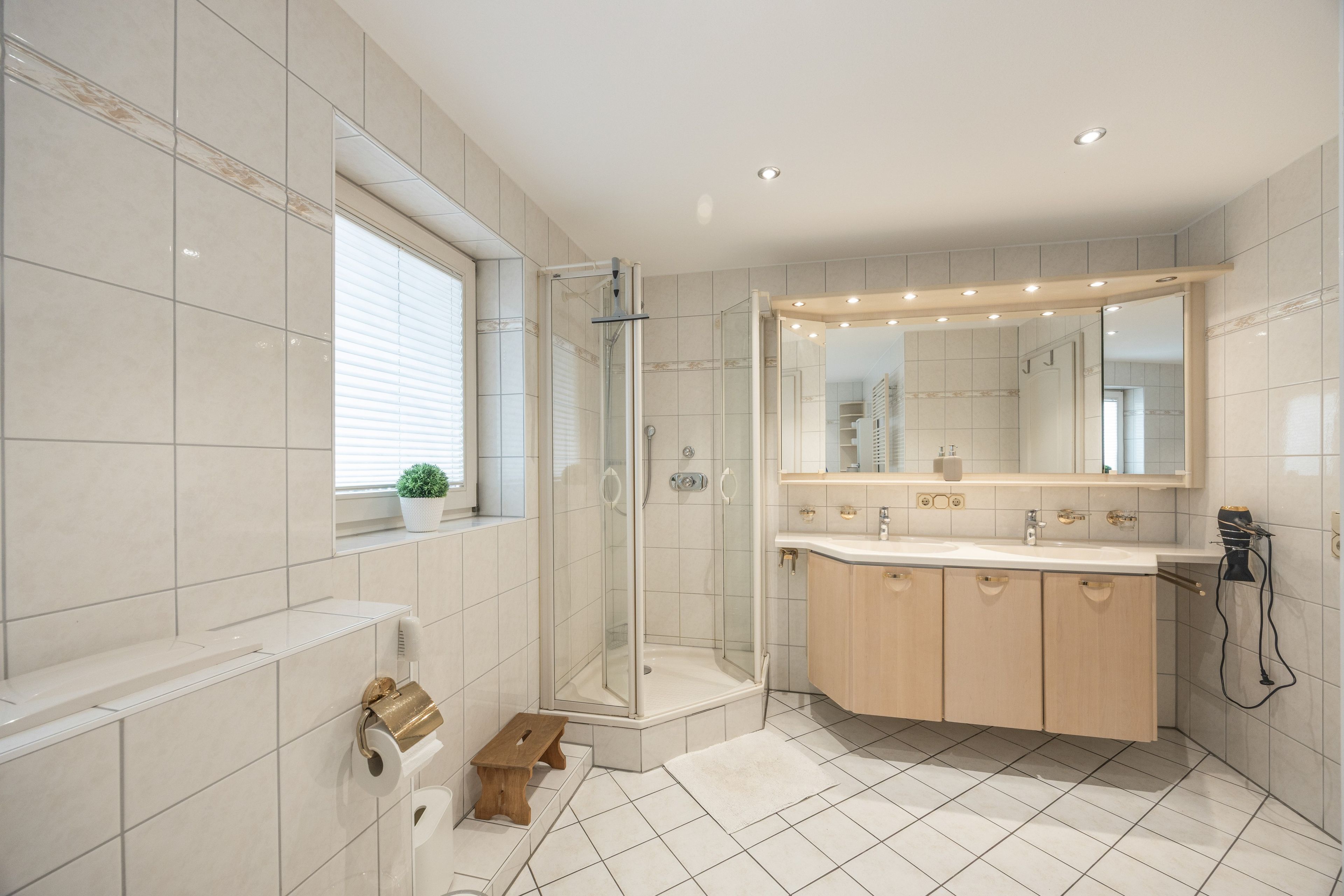 Een moderne badkamer met een inloopdouche, een grote spiegel en een wastafelmeubel met een wastafel.