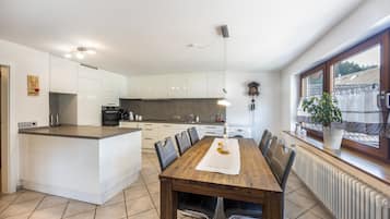 A modern kitchen with white cabinetry, a central island, and a dining area with a wooden table and chairs.