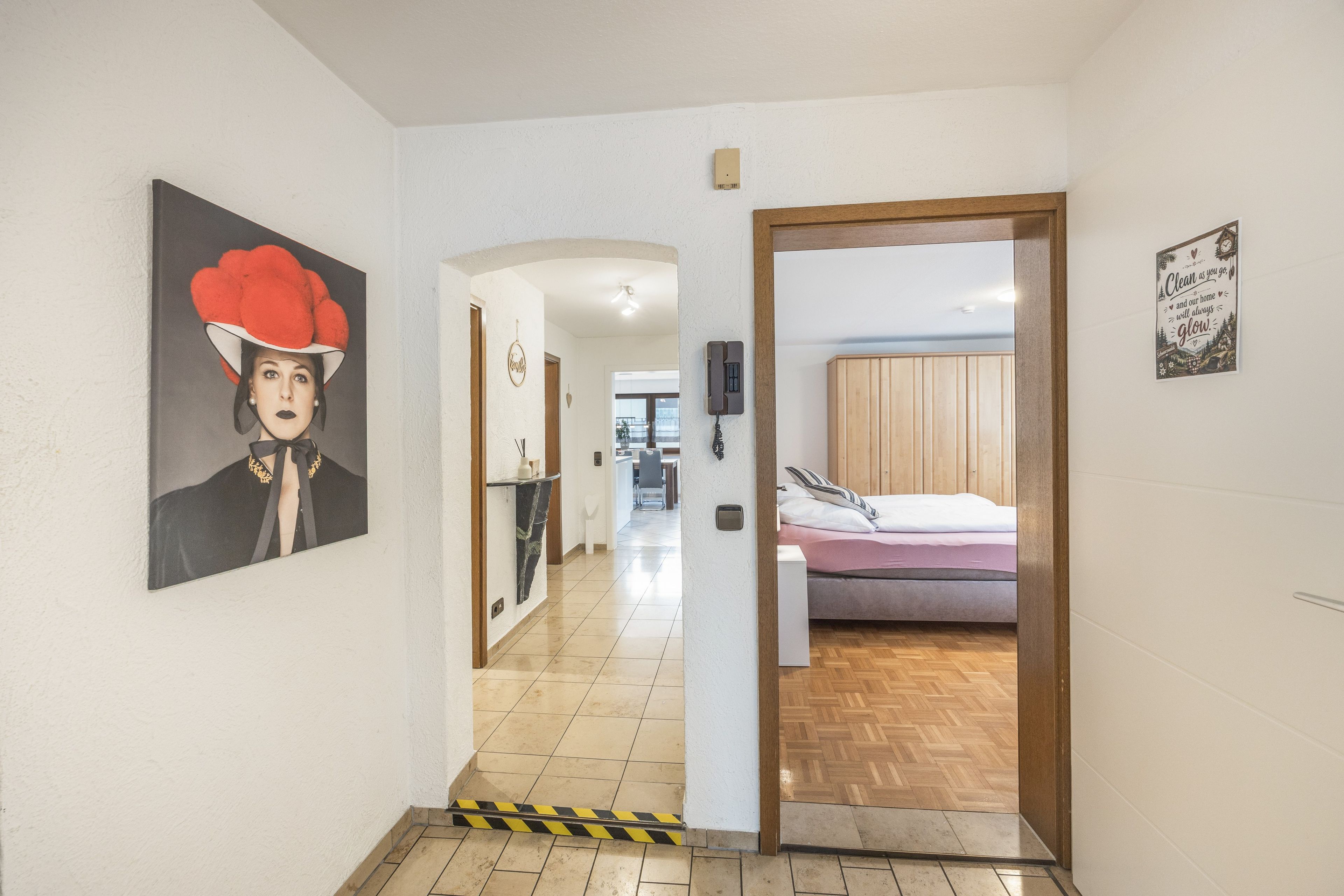 Ein Hotelgang mit einem Gemälde an der Wand, einer Holztür, die zu einem Zimmer führt, und einem Schild mit einer Aufschrift.