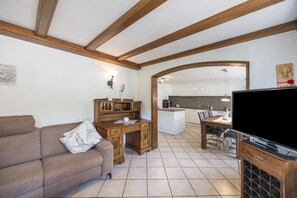A compact living space with a sofa, wooden desk, and a dining area. - Sommer Apartments Black Forest: Mountain View, Balcony & Wi-Fi – Family Friendly (Simonswald)
