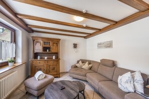 A cozy living room with a wooden ceiling, a built-in wooden cabinet, a beige sofa, and a small ottoman. - Sommer Apartments Black Forest: Mountain View, Balcony & Wi-Fi – Family Friendly (Simonswald)