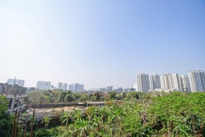 Un paisaje urbano con rascacielos, una obra en construcción y abundante vegetación.