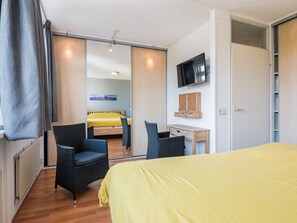 A hotel room with a bed, two chairs, a desk, a television, and a sliding door leading to another room. - Holiday Home in Bergen With Swimming Pool (Bergen)