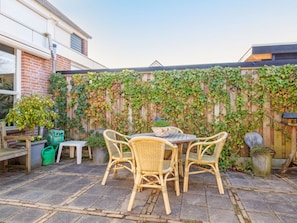 A patio with a table and chairs, surrounded by a brick wall covered in ivy. - Holiday Home in Bergen With Swimming Pool (Bergen)